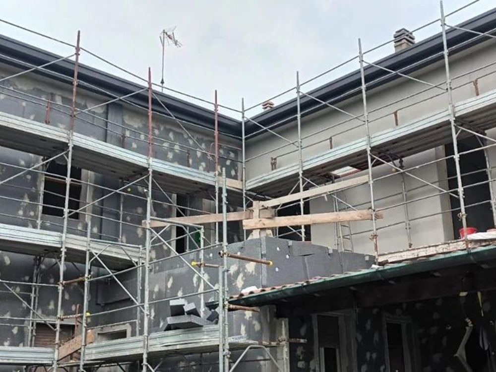 Posa del cappotto termico in EPS su edificio residenziale con ponteggio montato