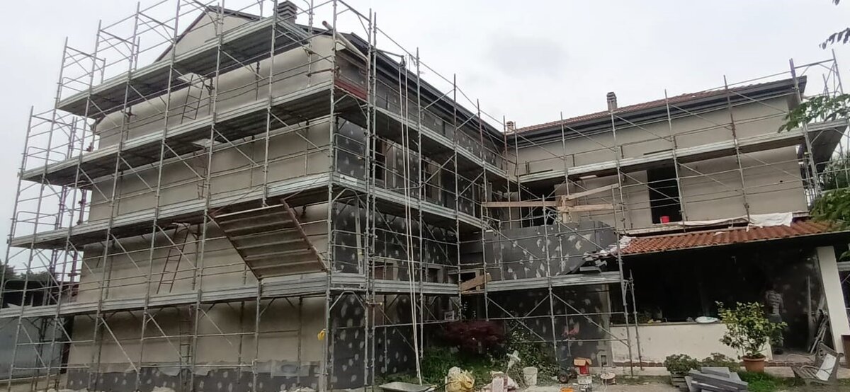 Edificio residenziale con cappotto termico in EPS in opera e ponteggio montato, cantiere a Barni
