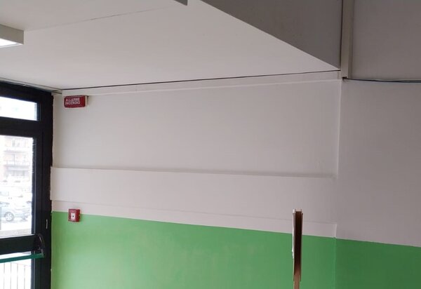 Atrio scolastico riconsegnato, con tinteggiatura bianca e verde e impianto antincendio